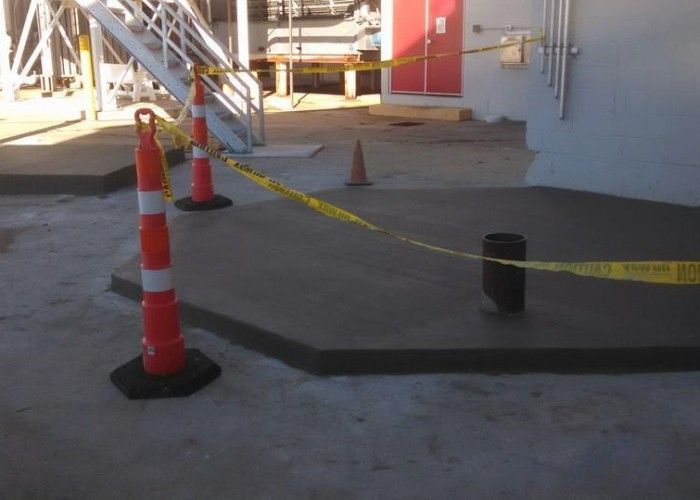 Construction area with orange cones and yellow caution tape blocking a paved walkway