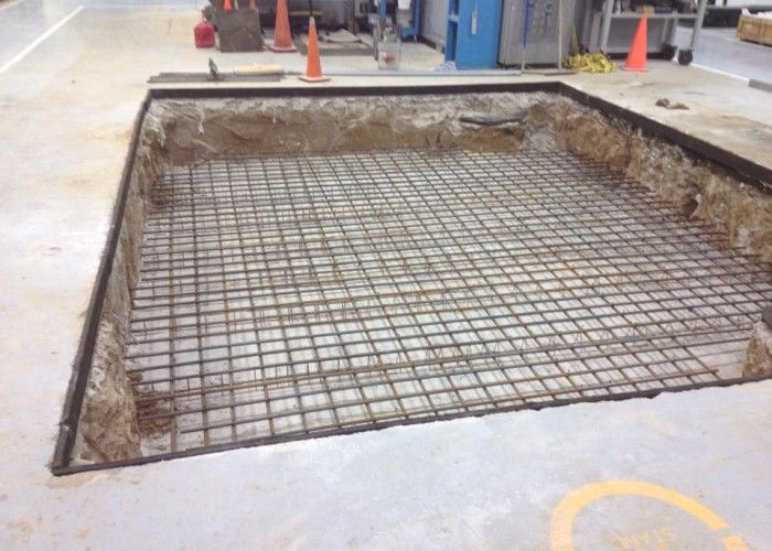 Large floor opening with exposed rebar grid in an industrial workshop area