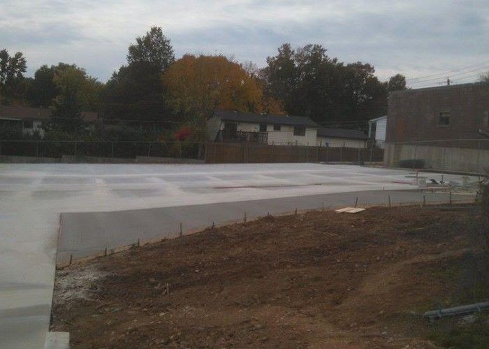 Empty ice rink under construction with a dirt foreground and trees in the background