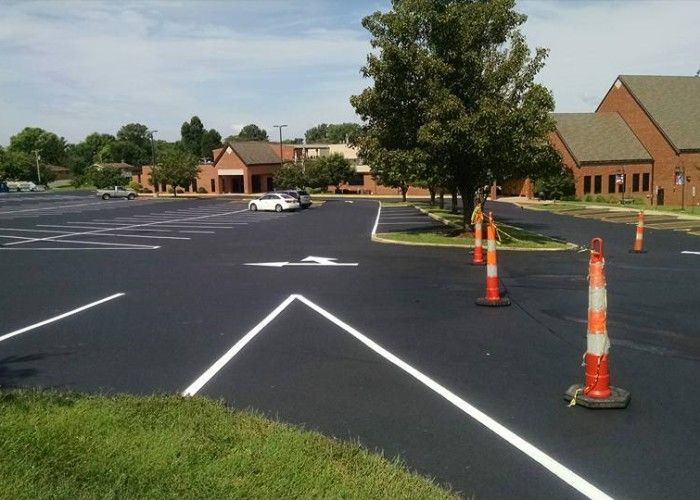 Parking lot with white directional markings and orange cones near brick buildings
