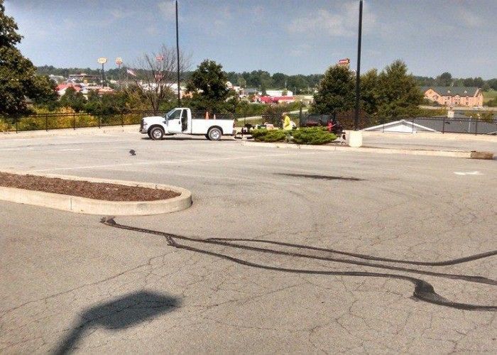 Empty parking lot with a white pickup truck, landscaped island, and buildings in the distance