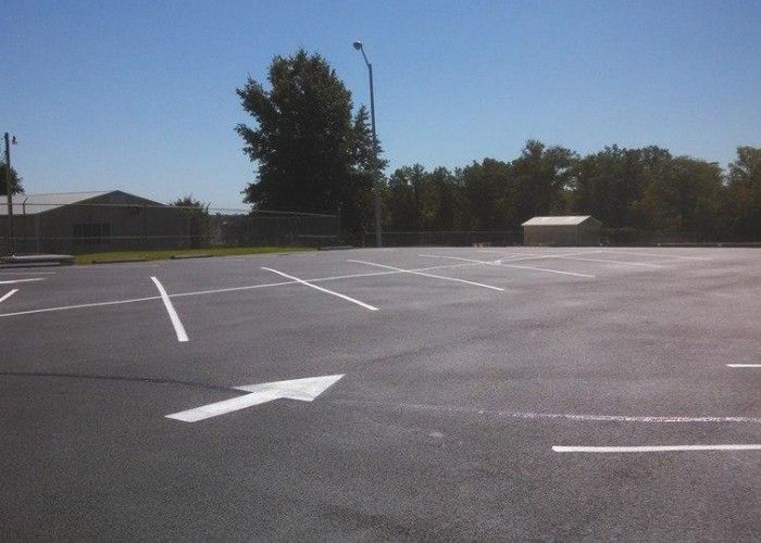 Empty parking lot with white painted lines and an arrow under a clear blue sky