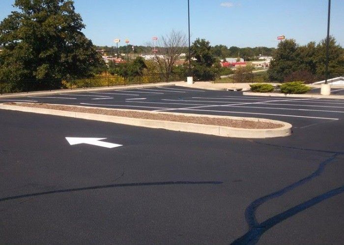 Empty parking lot with white directional arrows and a landscaped median under a clear sky