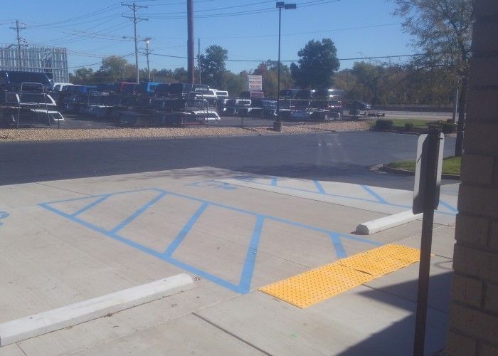 Accessible parking space with blue-striped access aisle and yellow curb ramp in a parking lot
