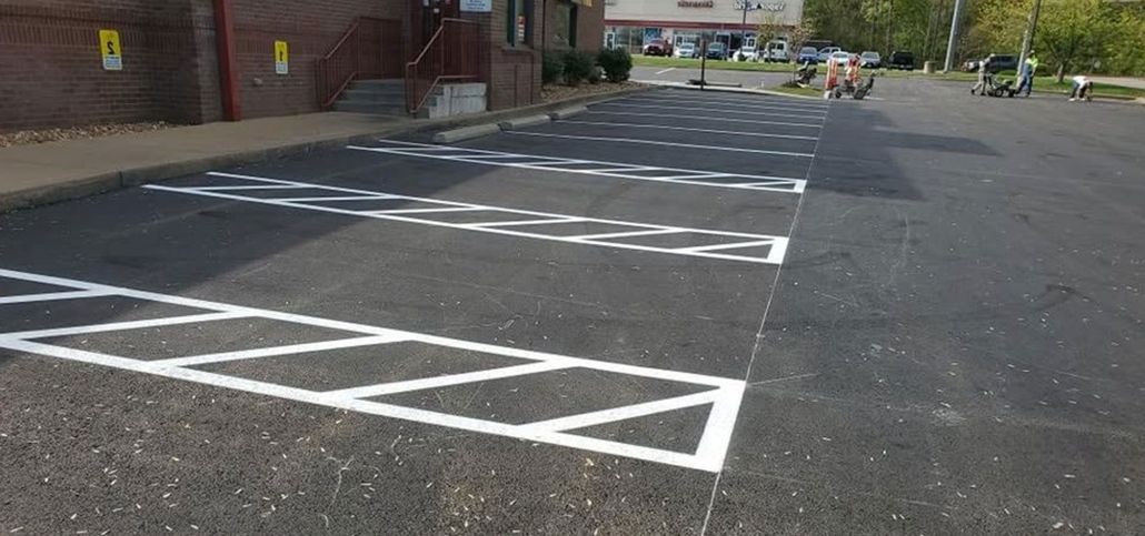 Empty parking lot with white marked spaces beside a brick building on a sunny day