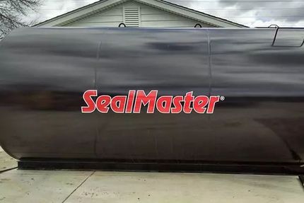 Black insulated tank with red SealMaster logo on a concrete pad in front of a building