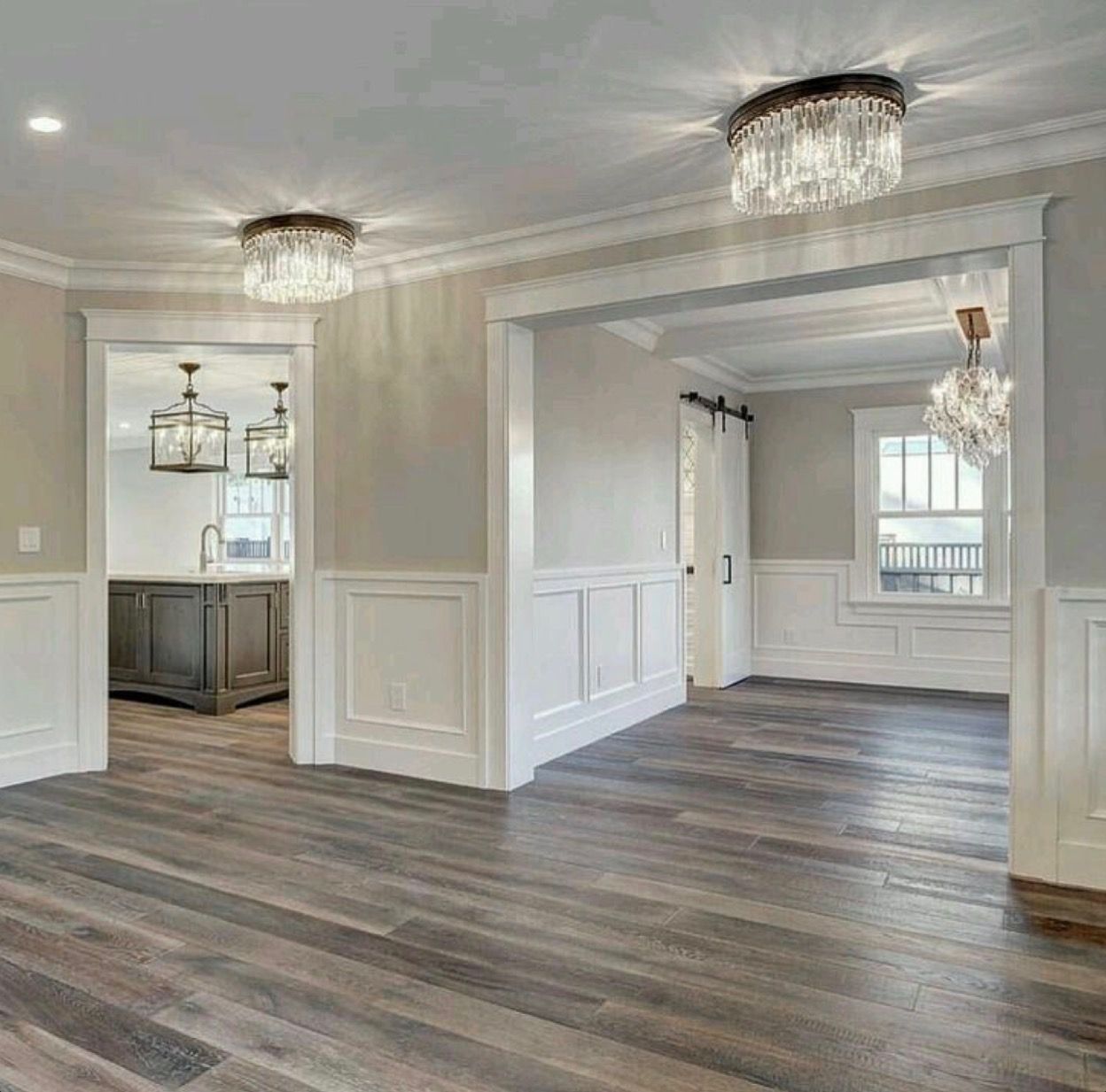 Bright empty dining room with white wainscoting, wood floors, and crystal chandeliers