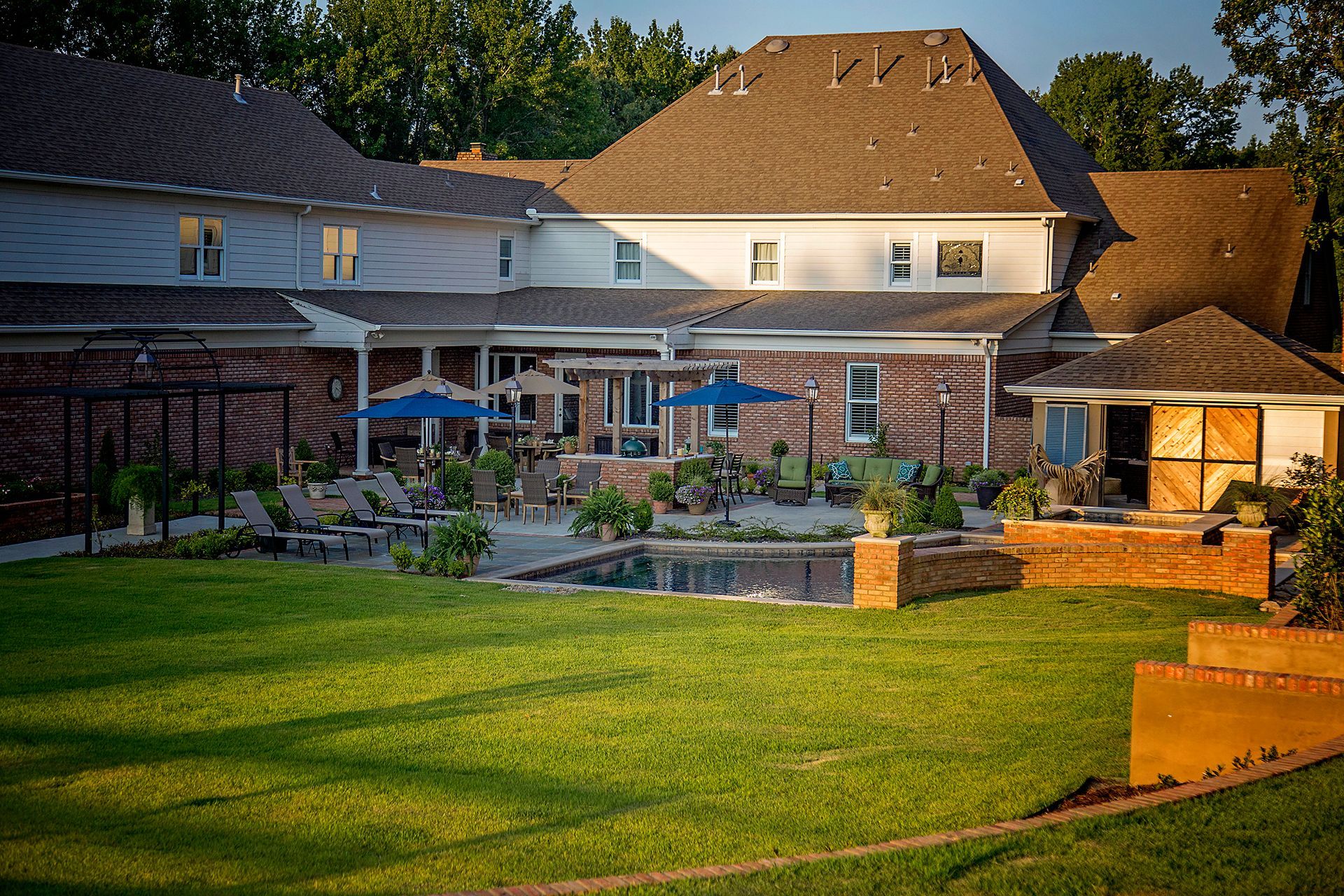 a large house with a large lawn and a pool in front of it .