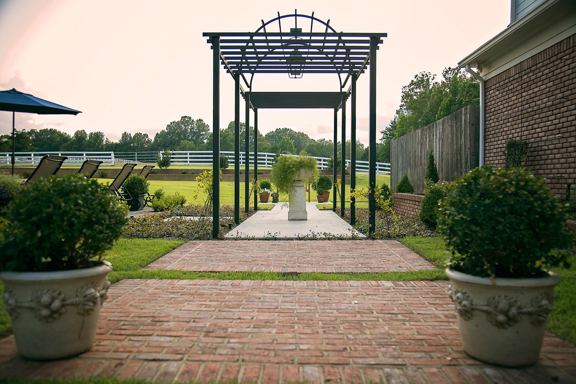 a brick walkway leading to a pergola in a backyard