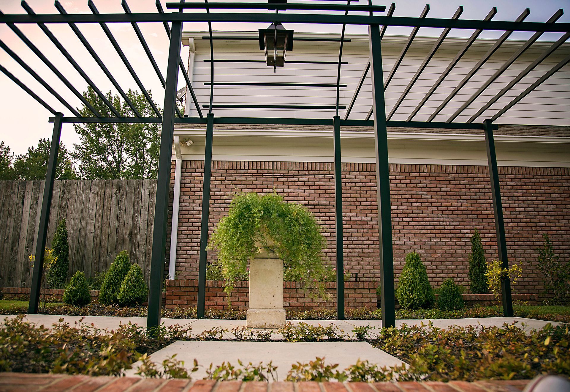 a brick wall with a pergola and a potted plant in front of it