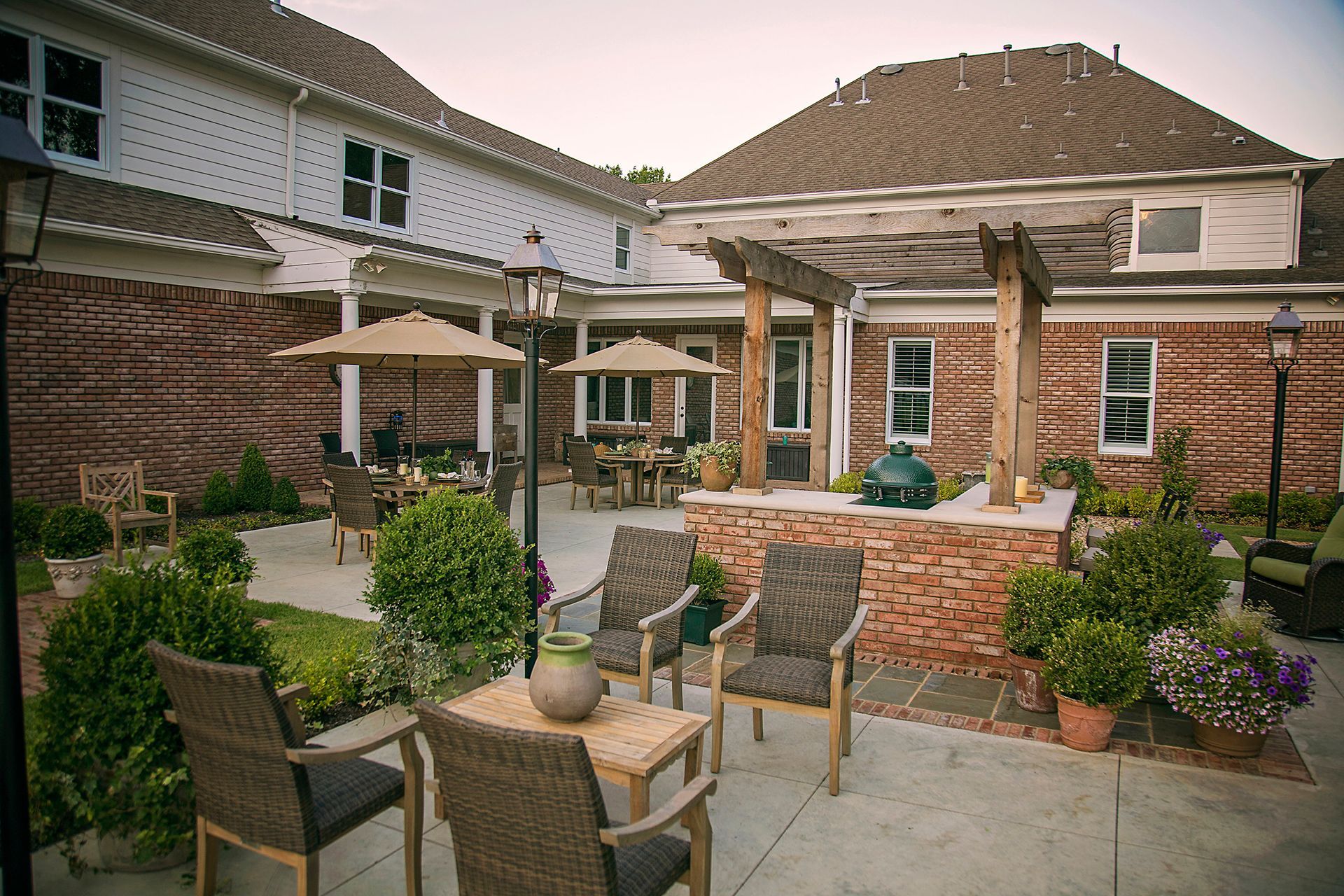 a patio with chairs , tables and umbrellas in front of a brick building .