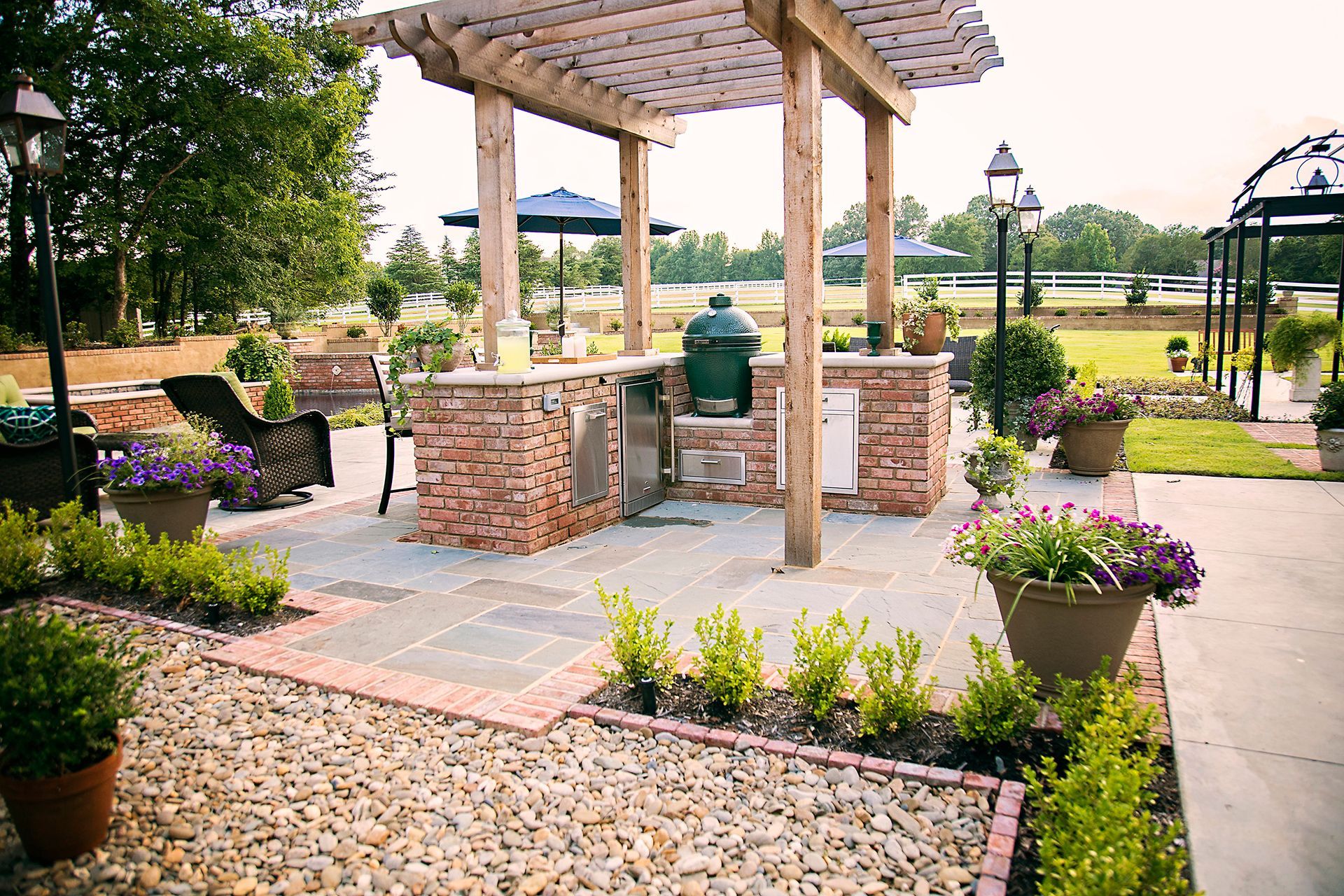 a patio with a pergola and a green grill
