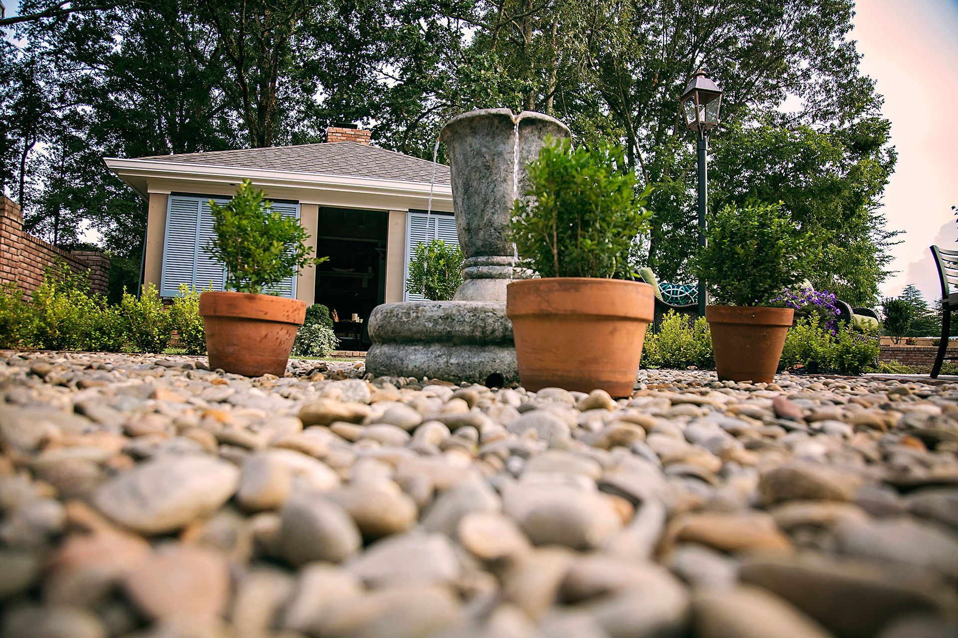 a fountain in a garden with potted plants in front of it .