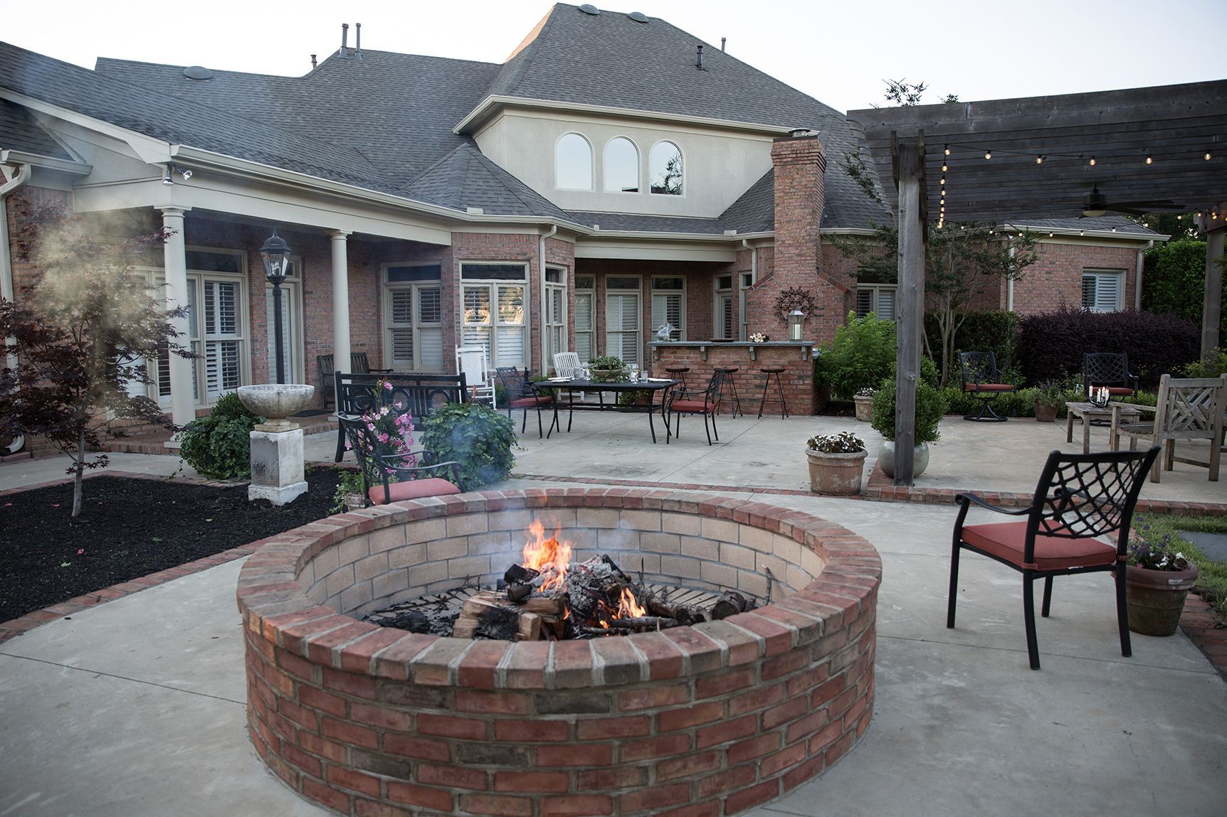 a fire pit is sitting on a patio with a house in the background.