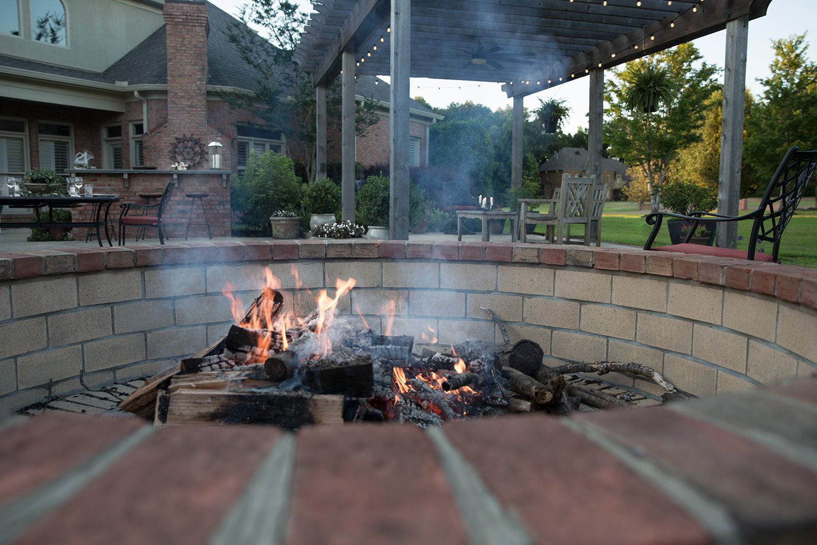 closeup view of a fire pit with a pergola behind it .