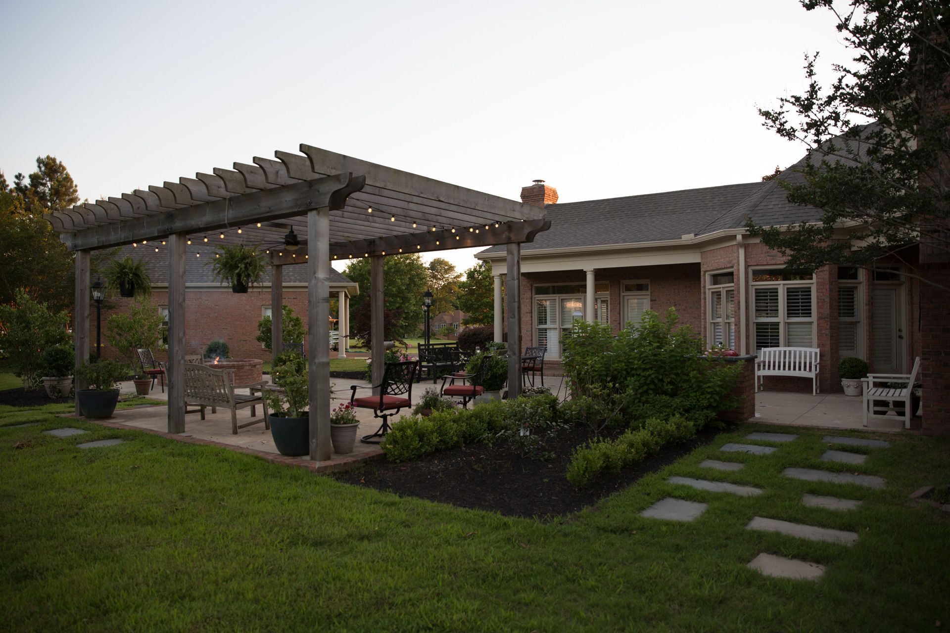 a pergola with landscaping behind a brick house