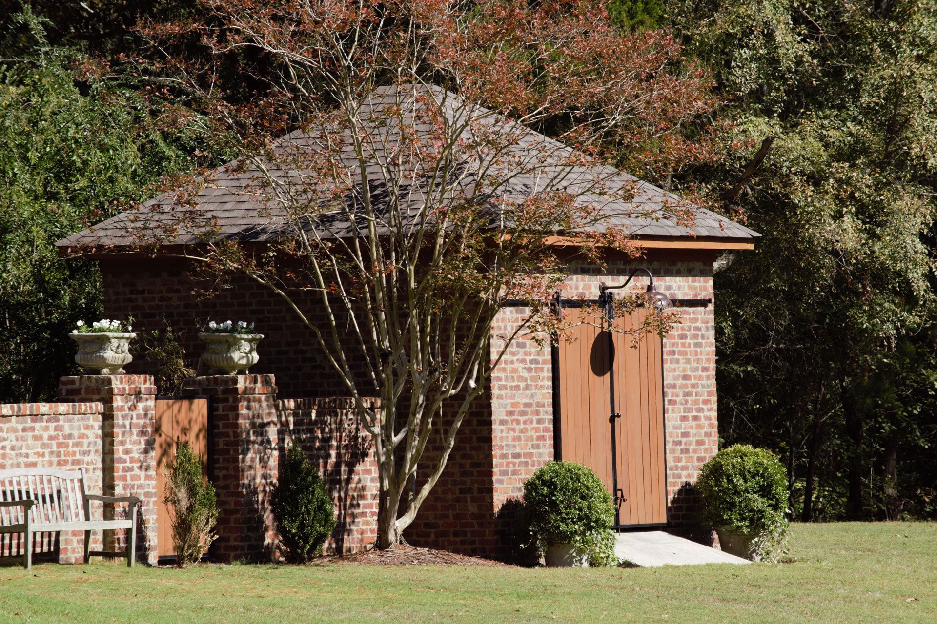 a brick outbuilding with a wooden door is in the middle of a back yard