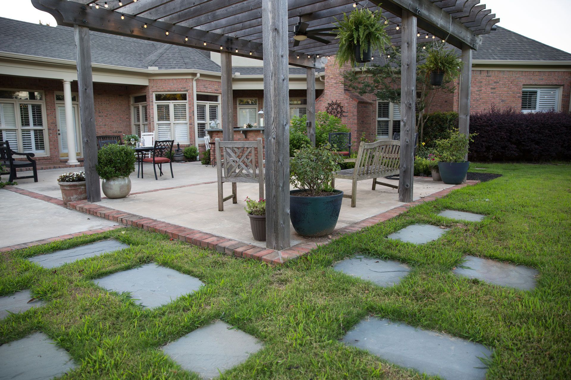a patio with a pergola , chairs , and potted plants