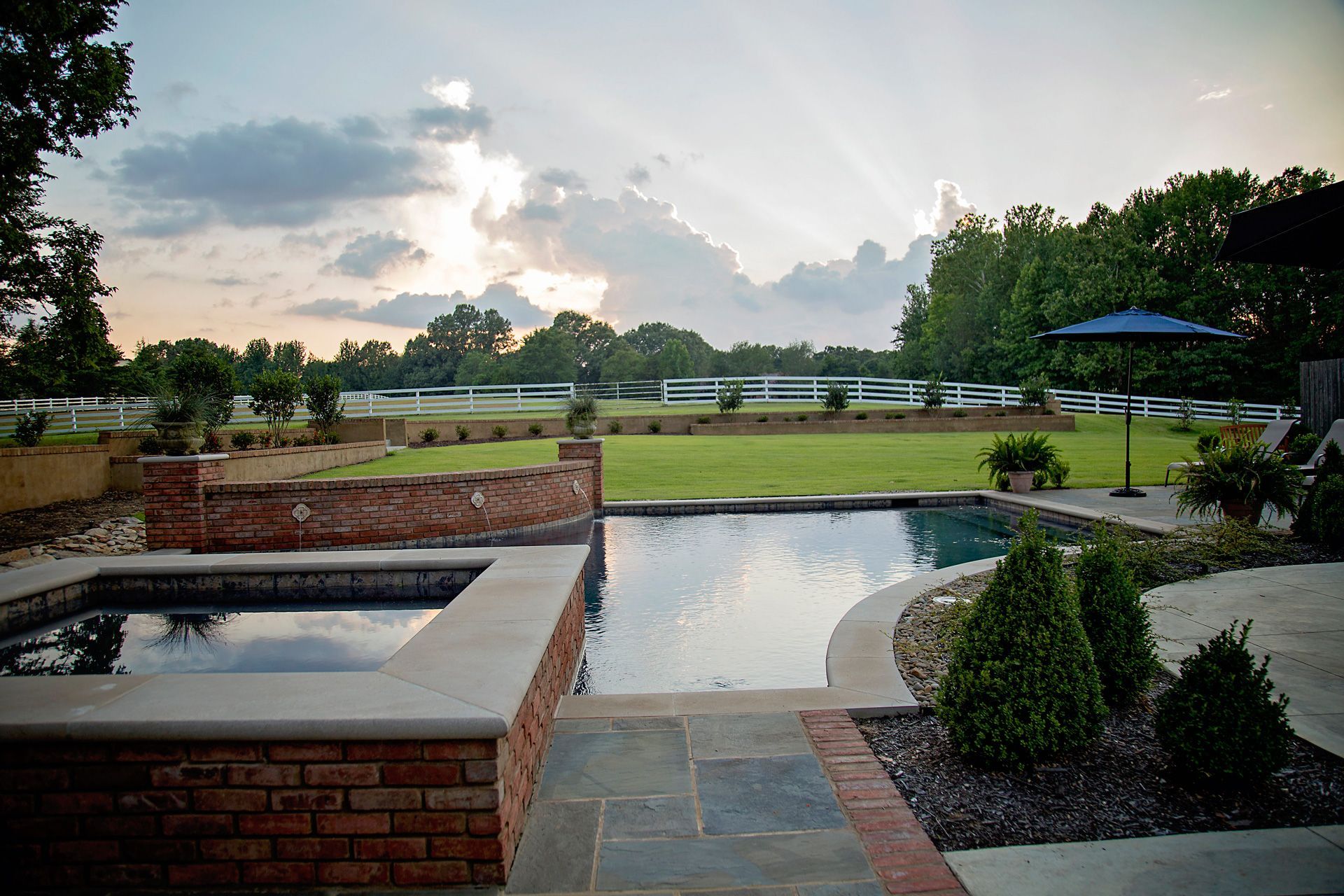 a large swimming pool in a backyard with a brick wall surrounding it