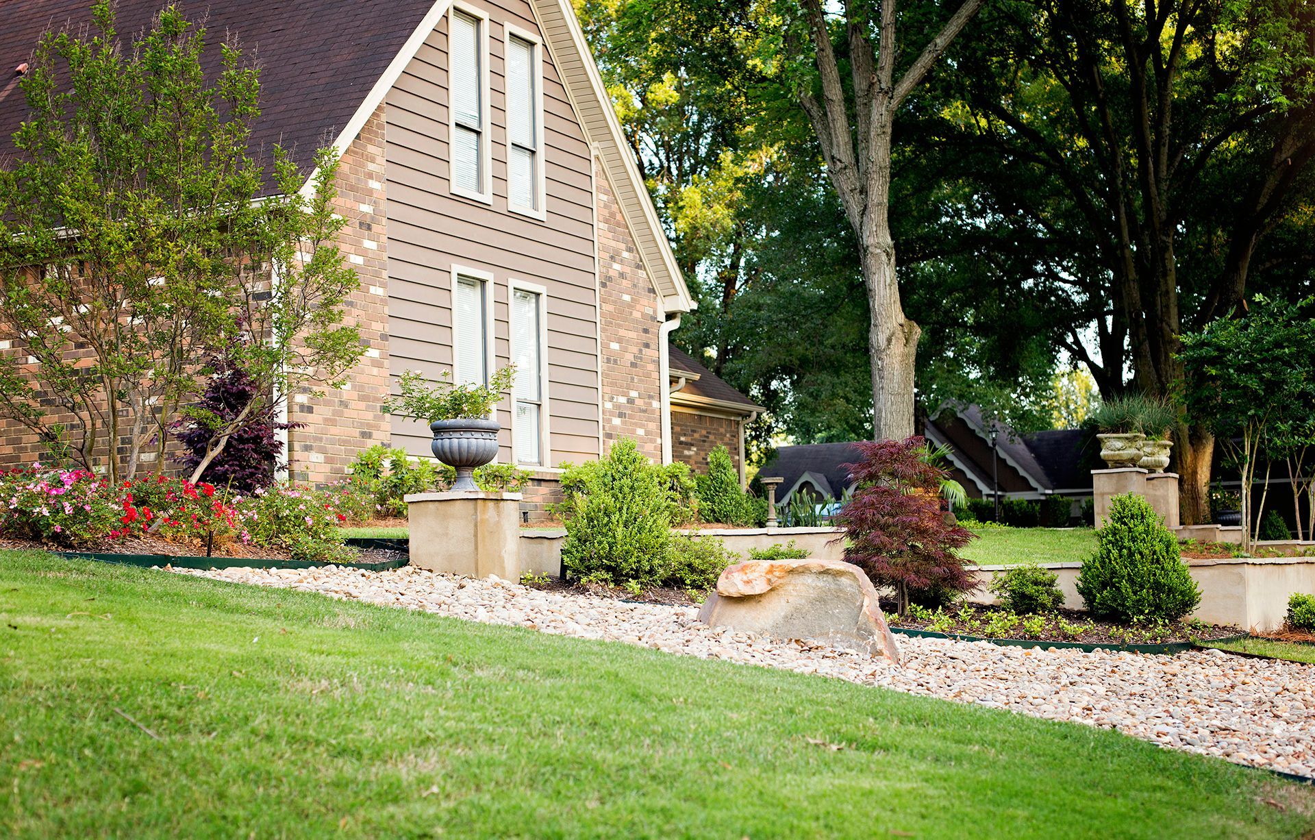 a large brick house with a lush green lawn in front of it .