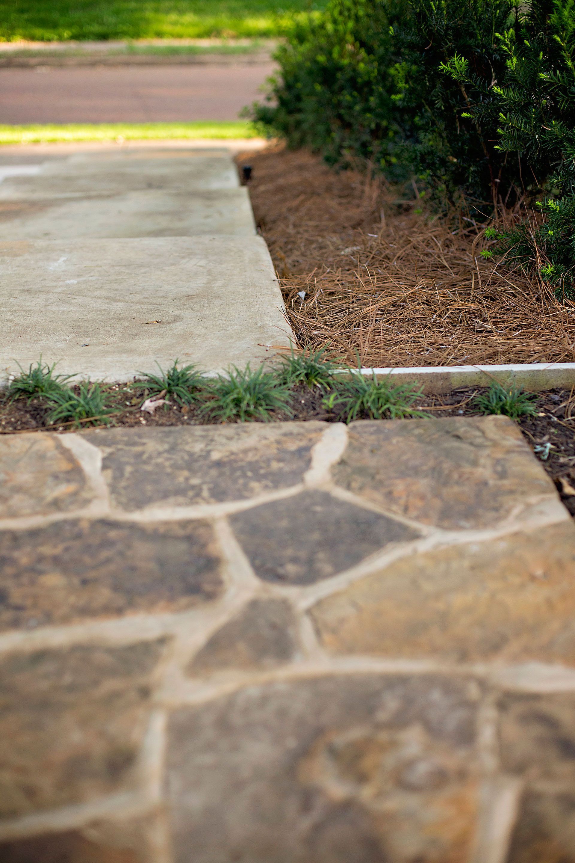 a close up of a stone walkway next to a concrete walkway .