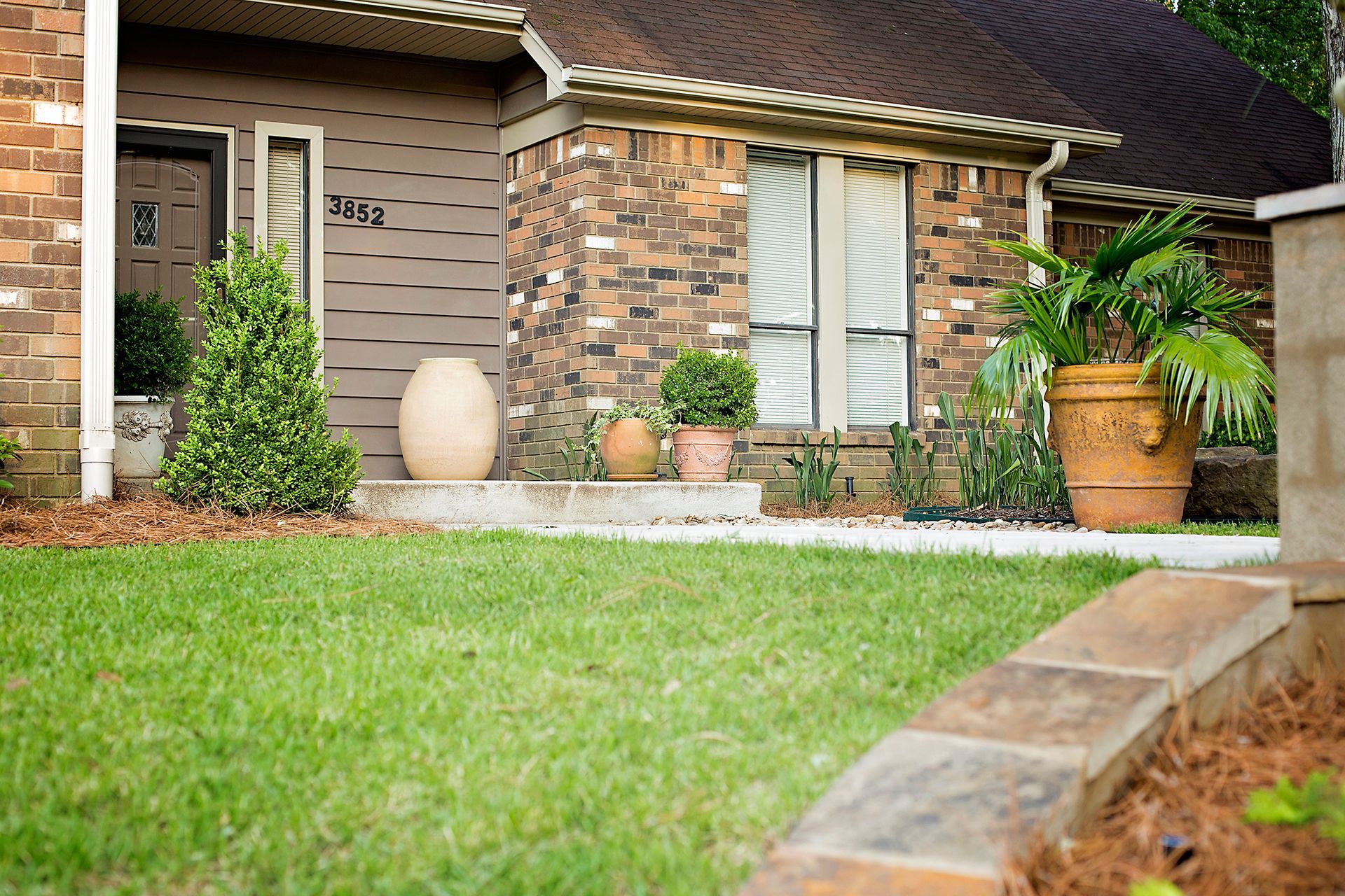 a brick house with a lush green lawn in front of it .