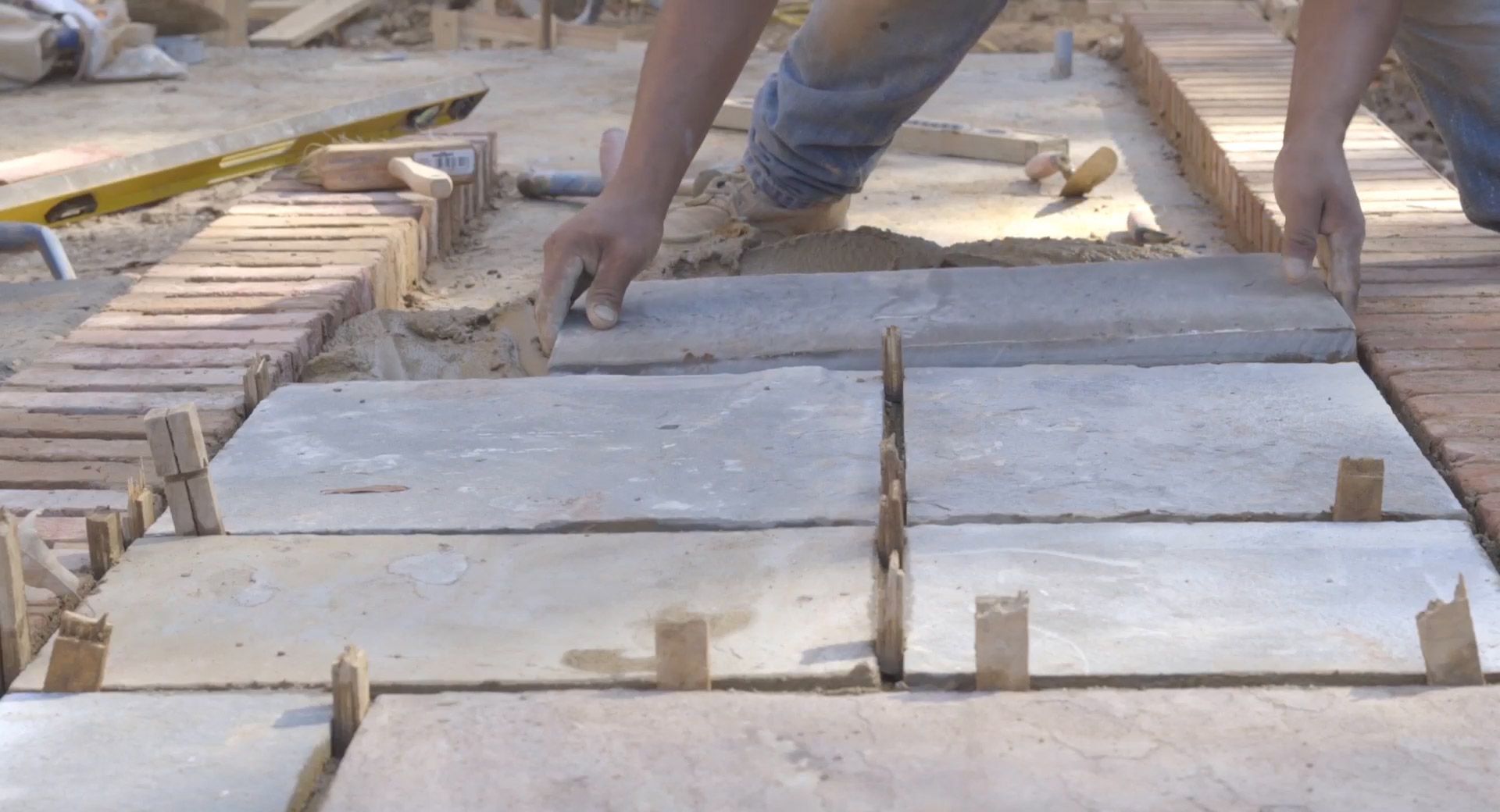 a worker is laying a stone walkway.