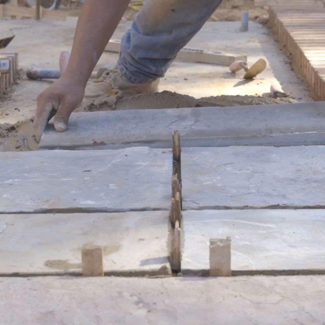 Worker laying flagstone pavers