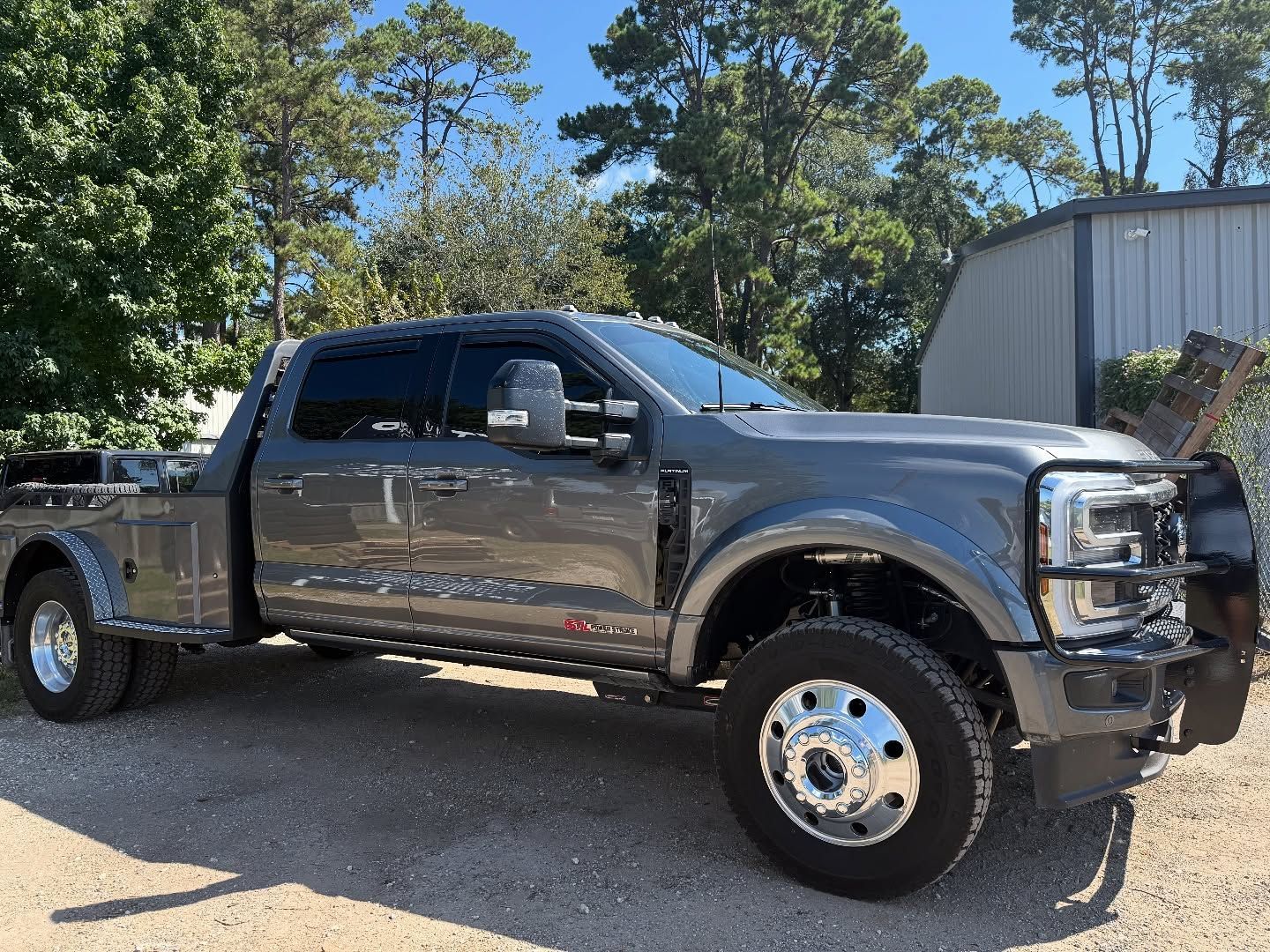 Gray Ford F-350 dually pickup truck with a flatbed, parked outside.