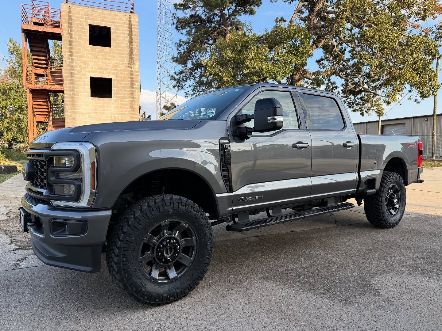 Gray Ford truck with black wheels parked near a building.