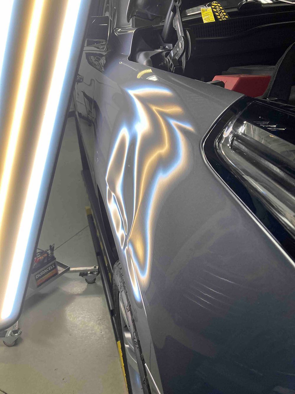 A car is sitting in a garage with a light shining on it.
