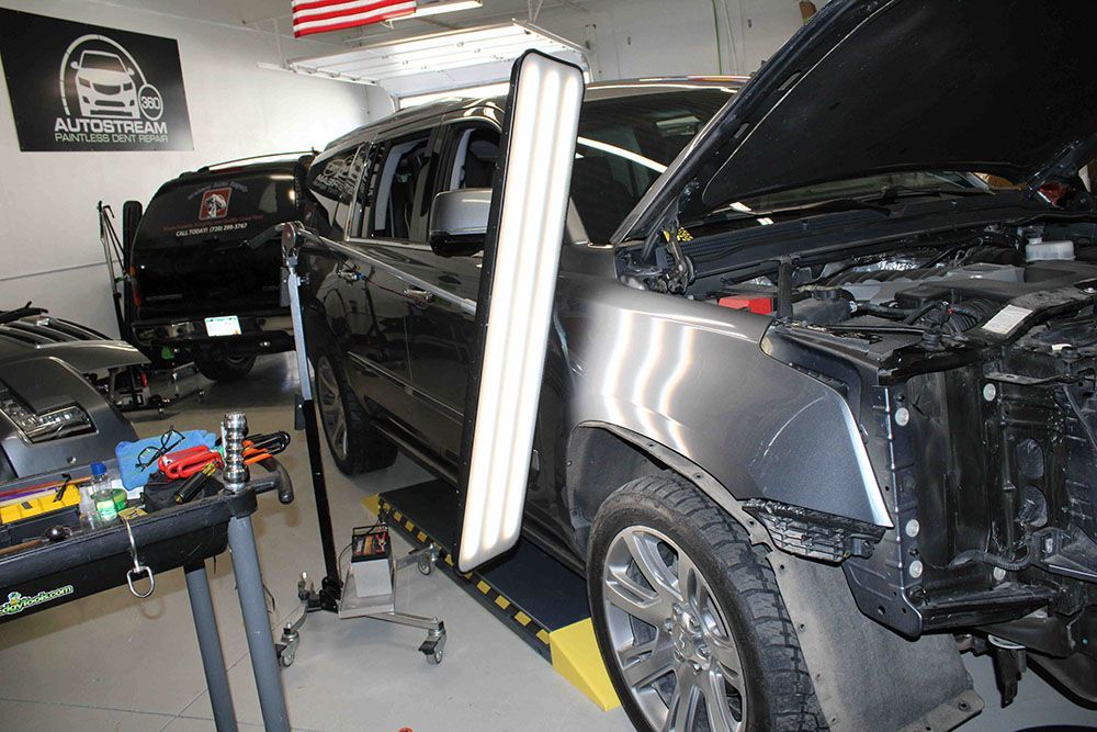 A car is being repaired in a garage with the hood open.