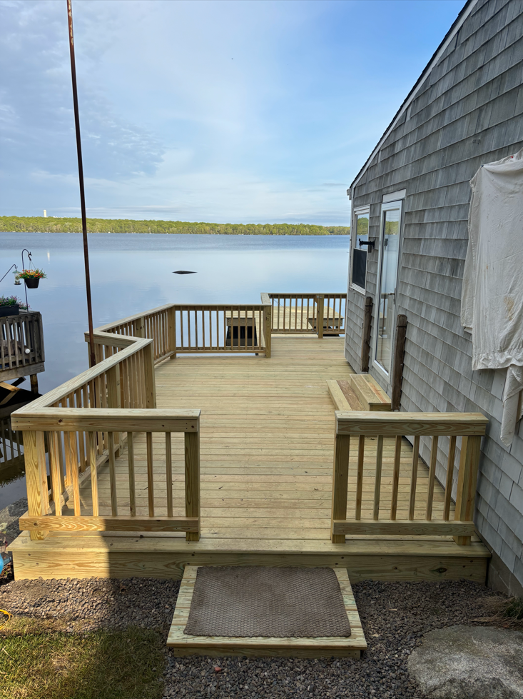 A wooden deck overlooking a body of water next to a house.