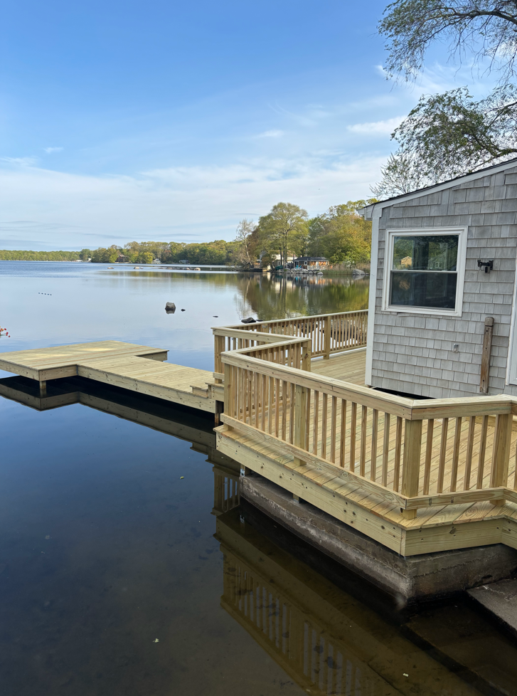 A house with a wooden deck overlooking a lake.