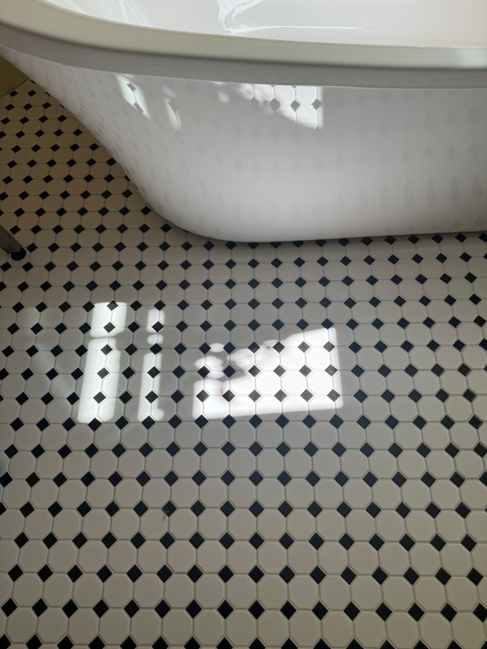 A bathtub on a black and white tiled floor