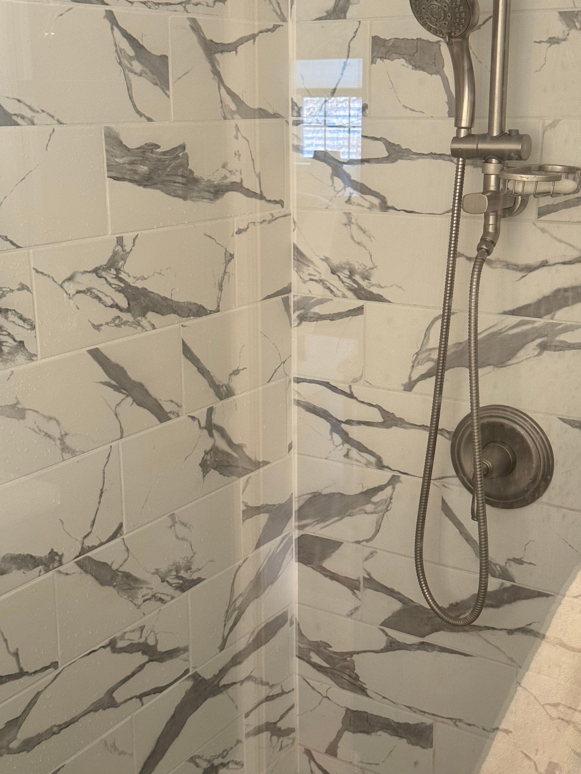 A shower area with marble tiles and a shower head