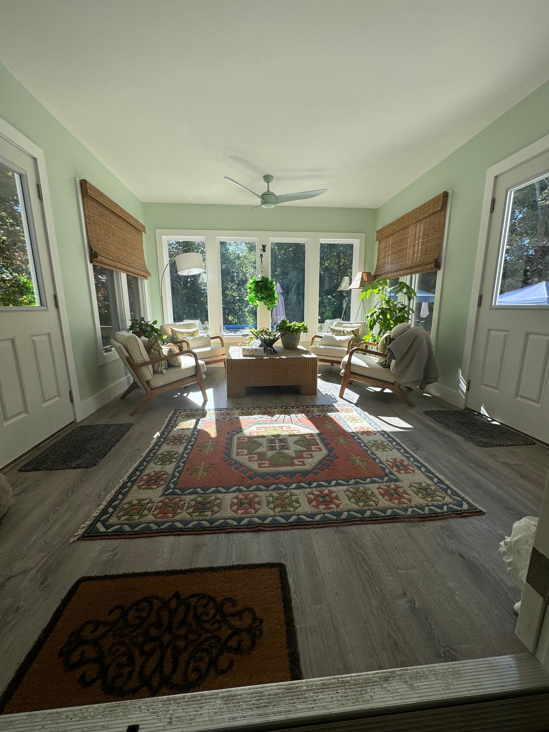 A living room with a rug, chairs, a center table, and a ceiling fan.