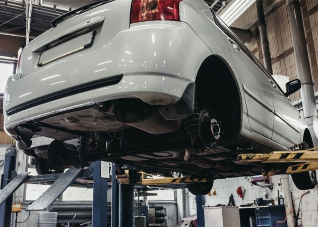 A white car is sitting on a lift in a garage.