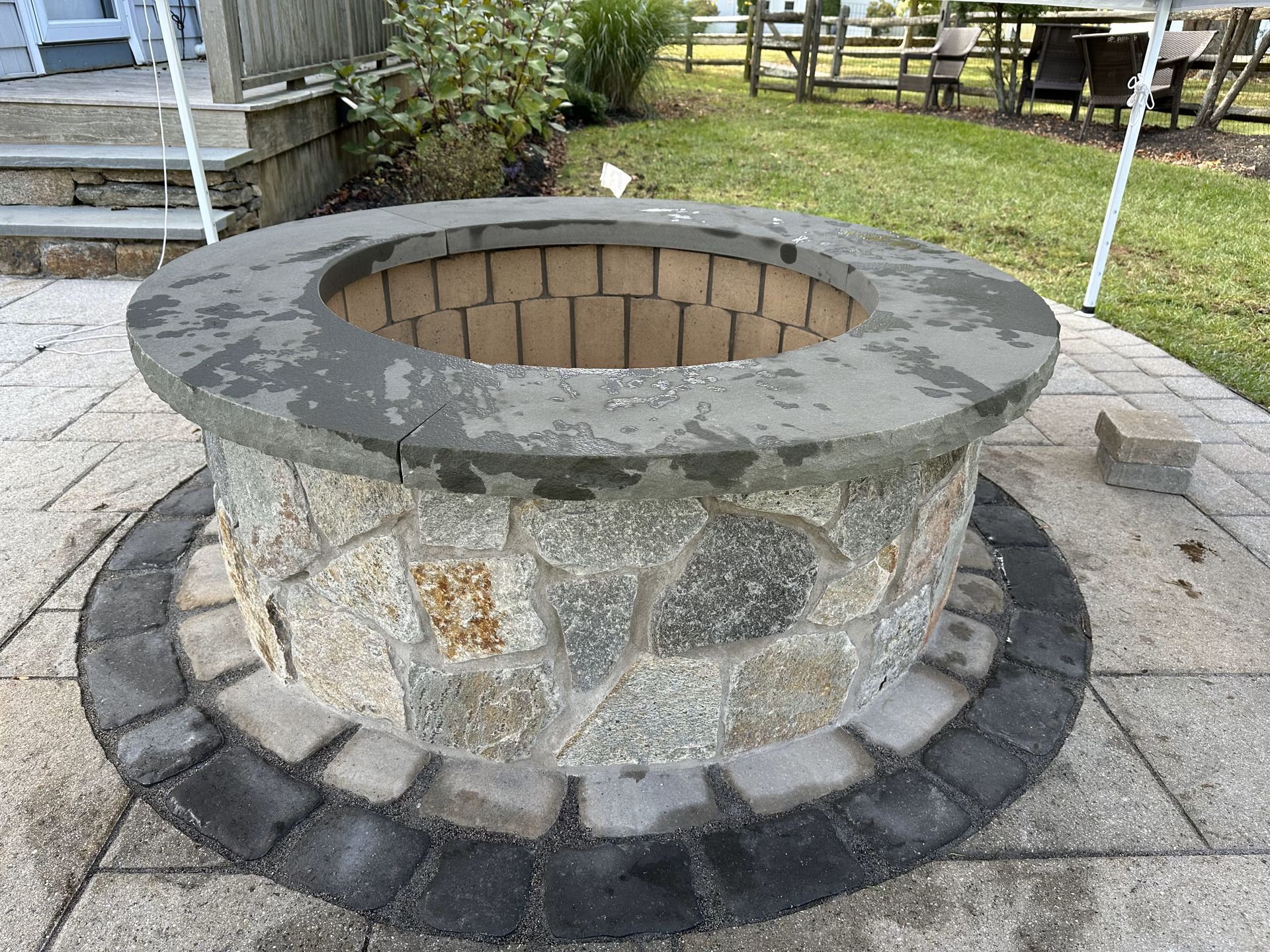 A fire pit is sitting on a patio next to a lawn.