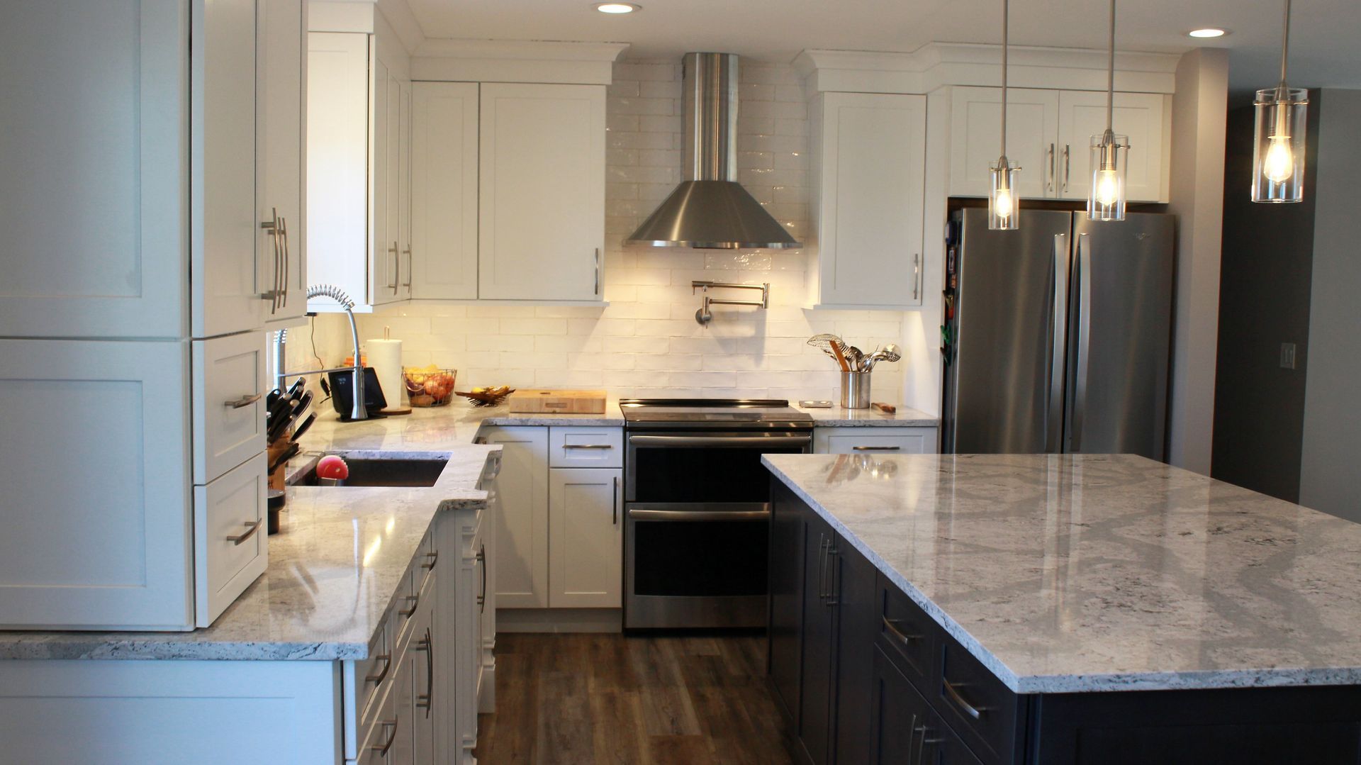 Modern kitchen with white and dark blue cabinets, stainless steel appliances, and granite countertops.