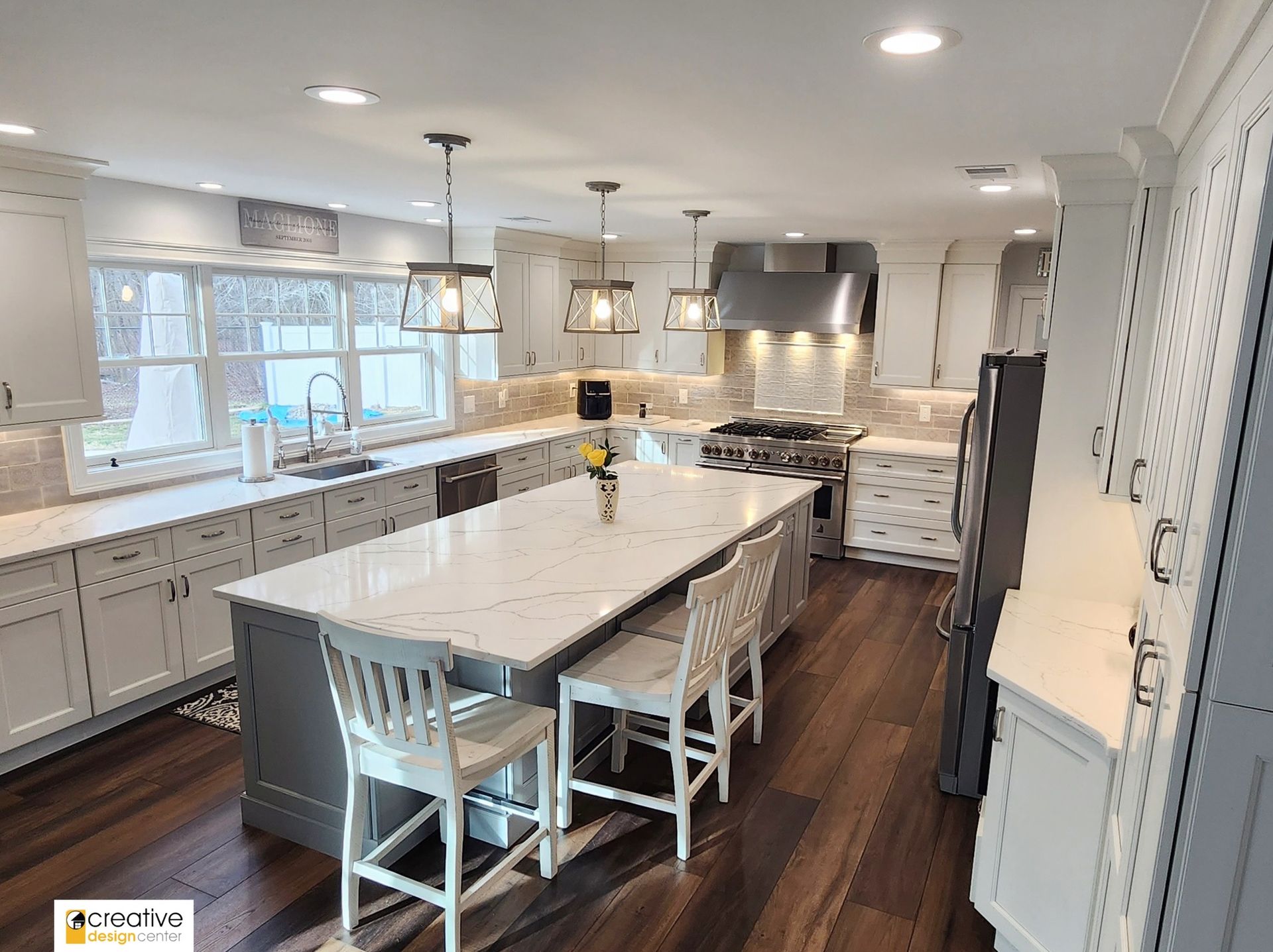 A kitchen with white cabinets and a large island in the middle.