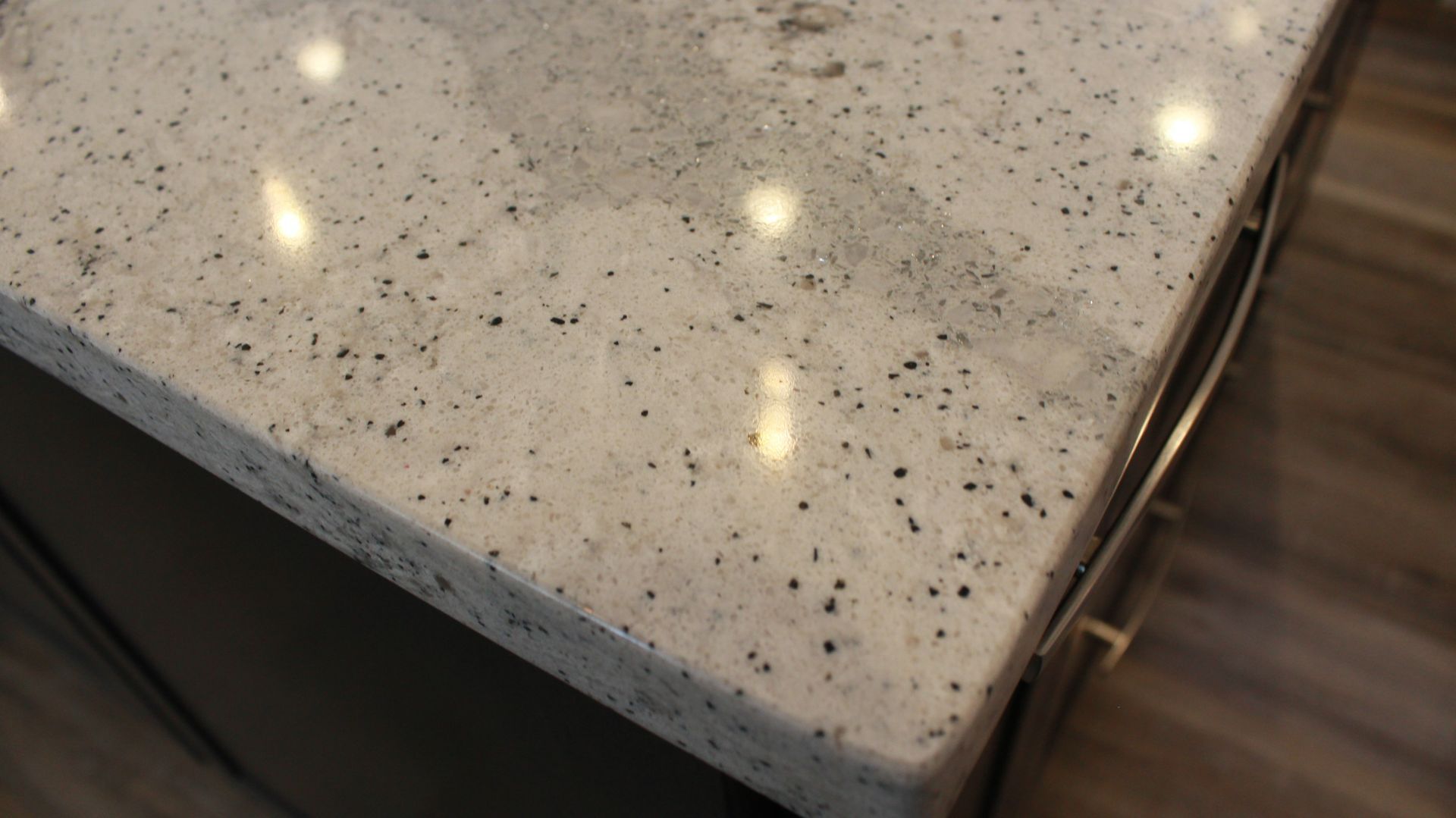 Close-up of a speckled granite countertop with dark flecks, on a dark-toned cabinet.