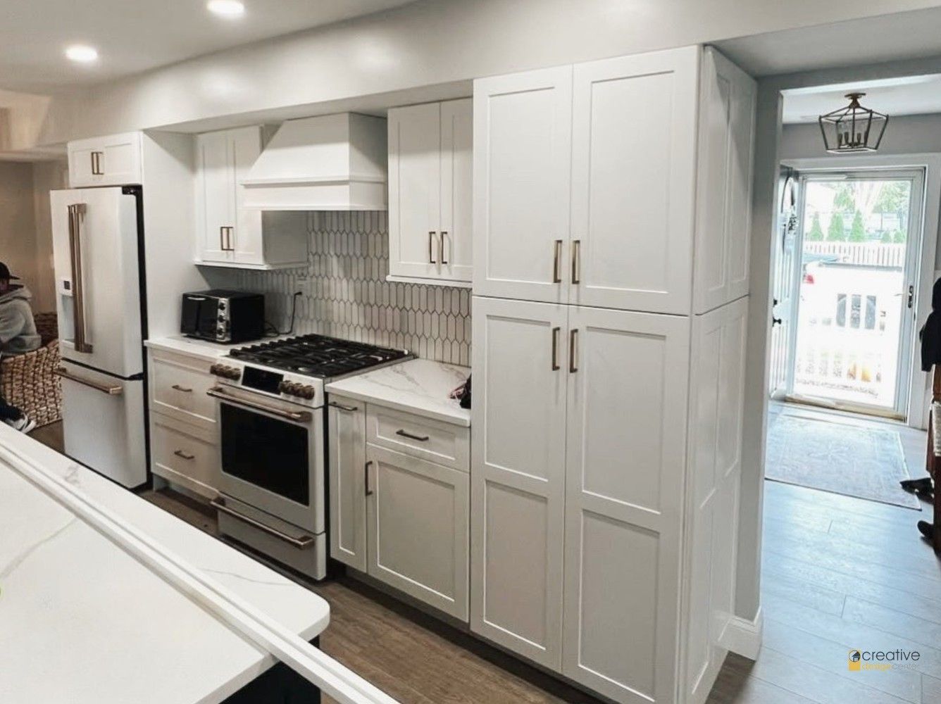 A kitchen with white cabinets, a stove, a refrigerator, and a microwave.