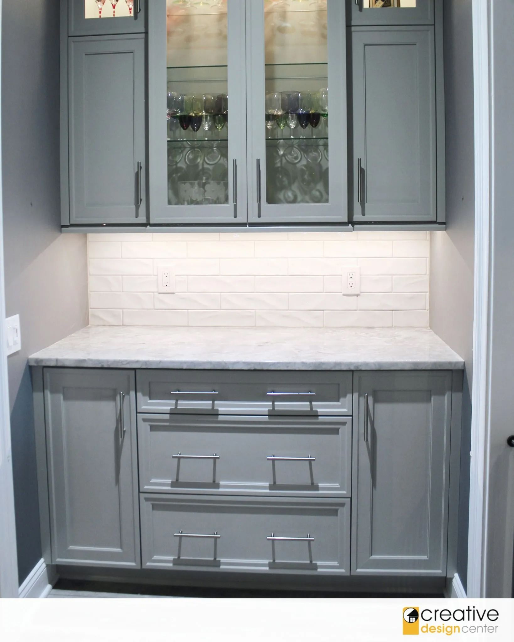 A kitchen with gray cabinets and white counter tops