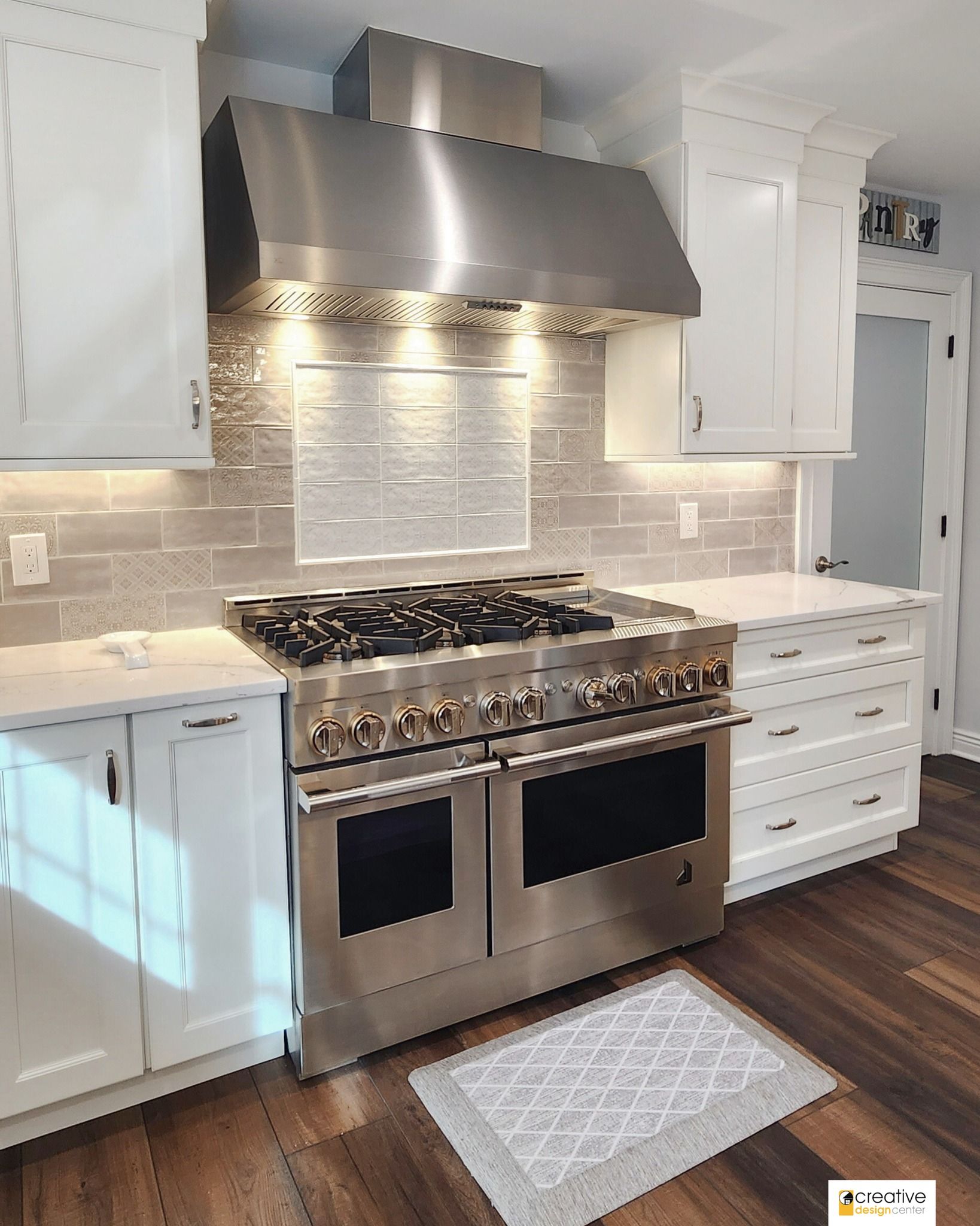 A kitchen with stainless steel appliances and white cabinets.