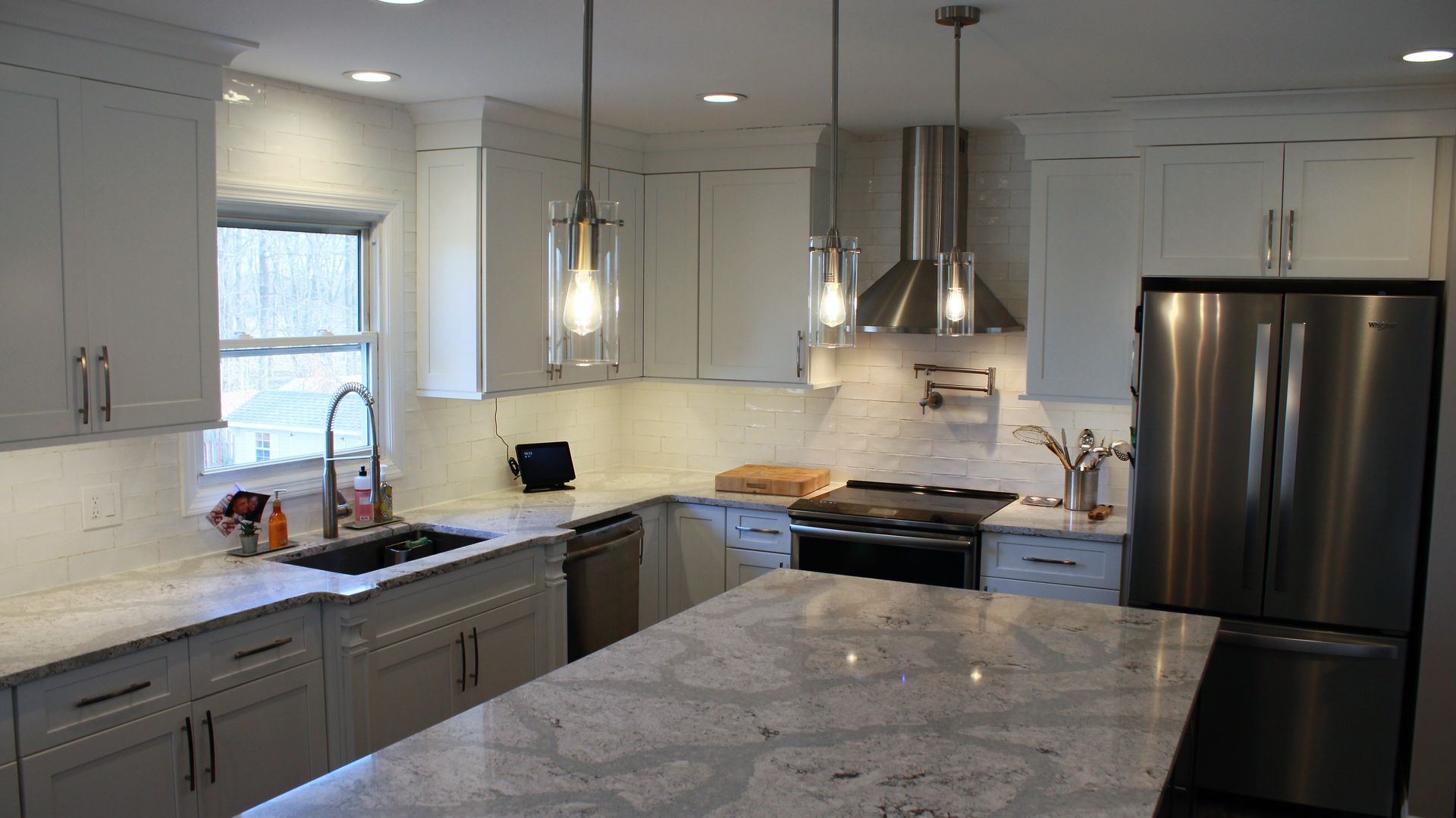 Kitchen with white cabinets, a granite island, and French doors leading outside.