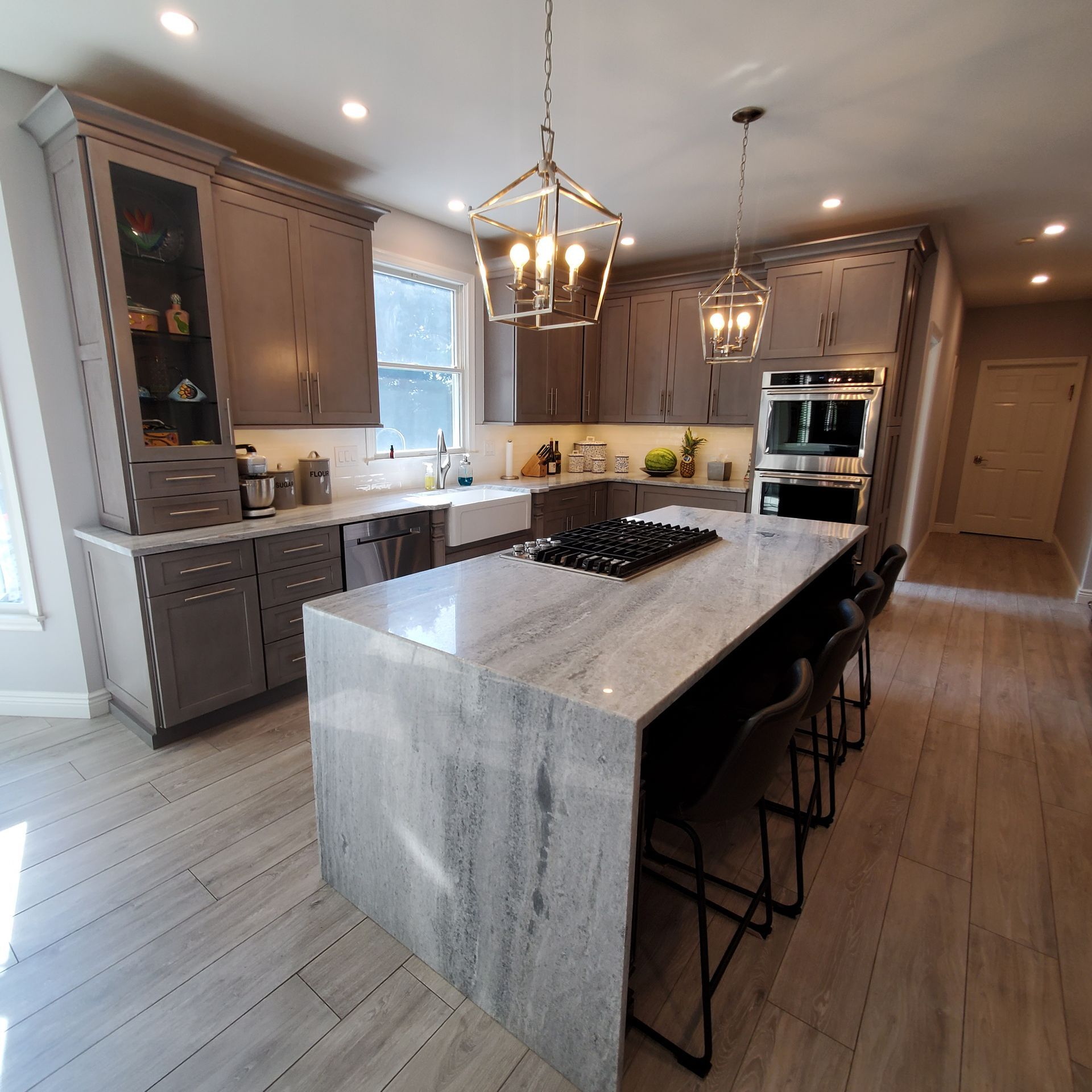 Modern kitchen with grey cabinets, large island, and stainless steel appliances.