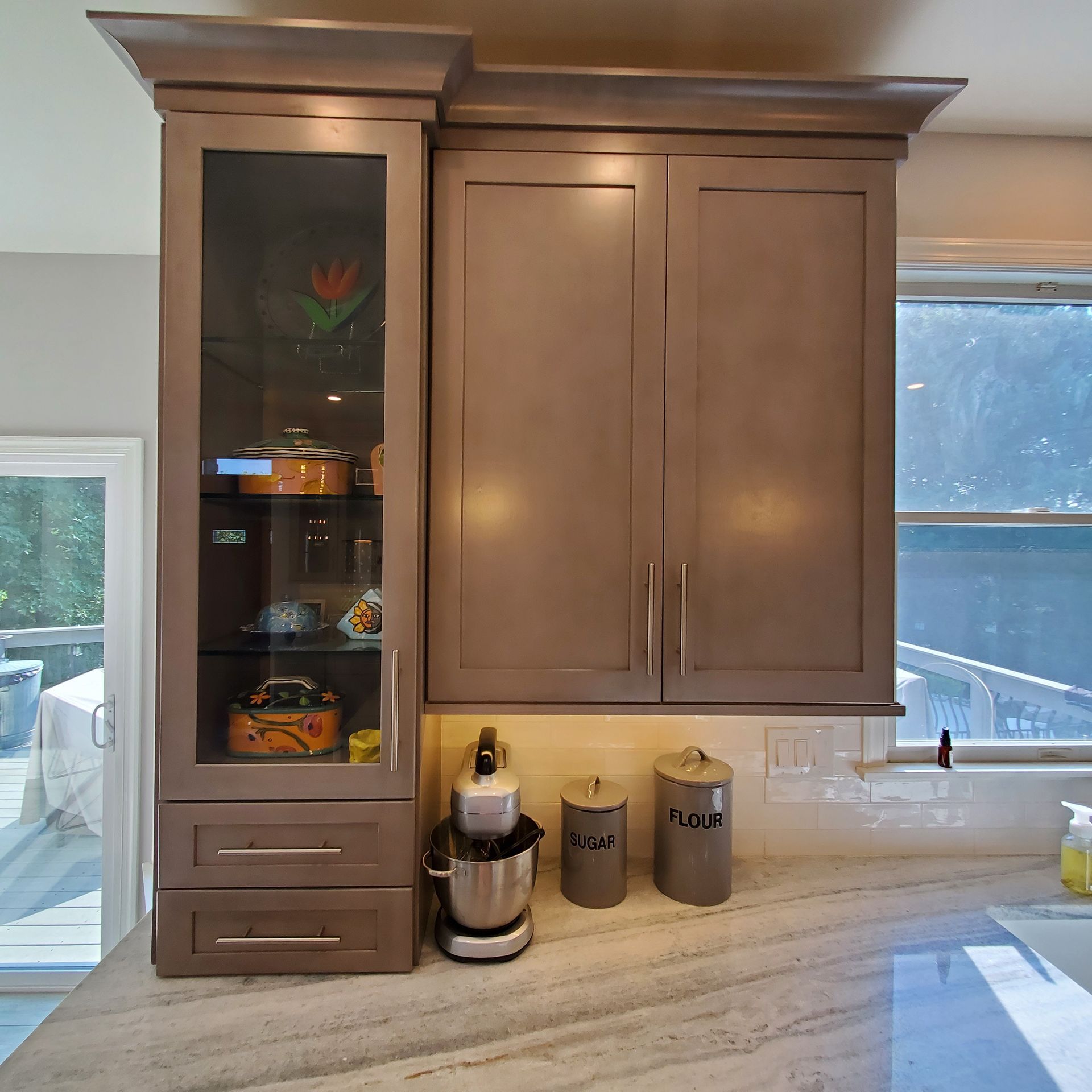 Gray kitchen cabinets above a countertop. Glass-front cabinet on the left, two solid doors on the right.
