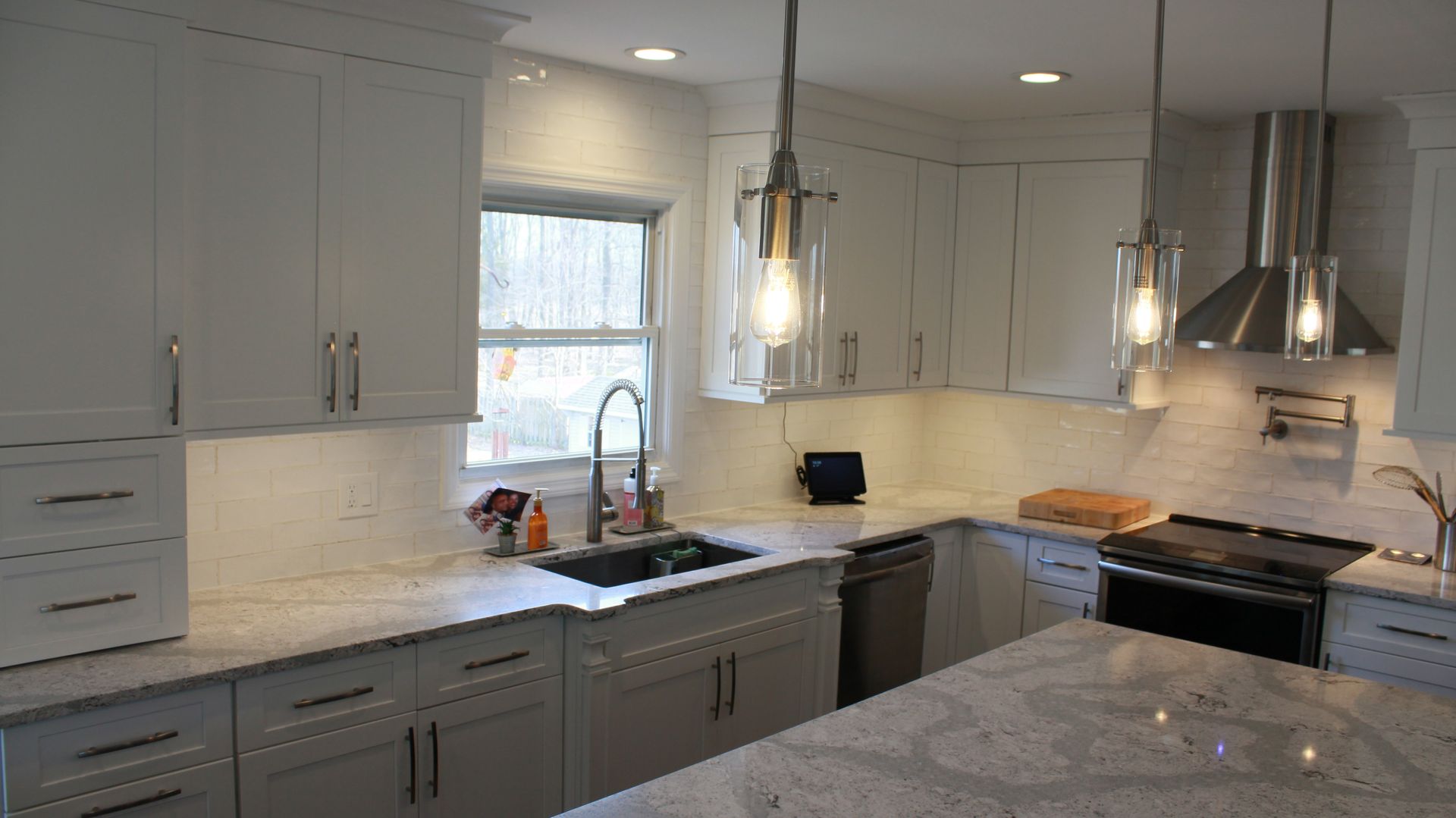 White kitchen with cabinets, countertop, sink, window, stove, and island.