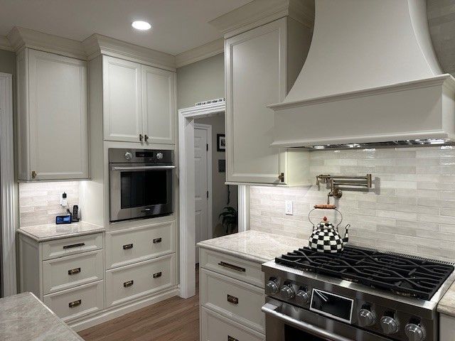 White kitchen with oven, range, cabinets, and light-colored countertops.